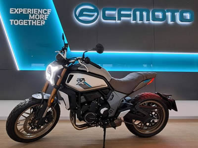 CFMOTO 700CL-X Heritage - pohled na stojící motorku ve stříbrné barvě s hnědým koženým sedlem